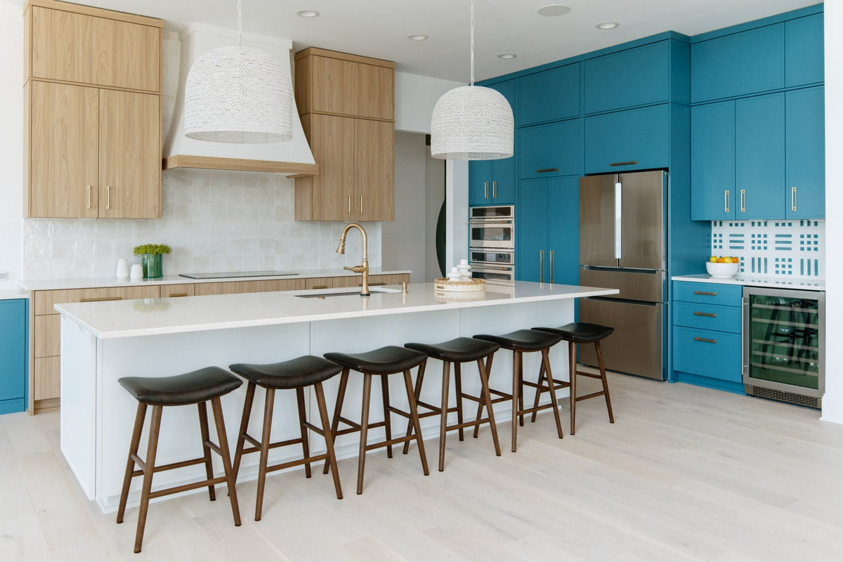 A teal kitchen in Panora with brass pulls on floor to ceiling cabinets and a graphic tile backsplash.