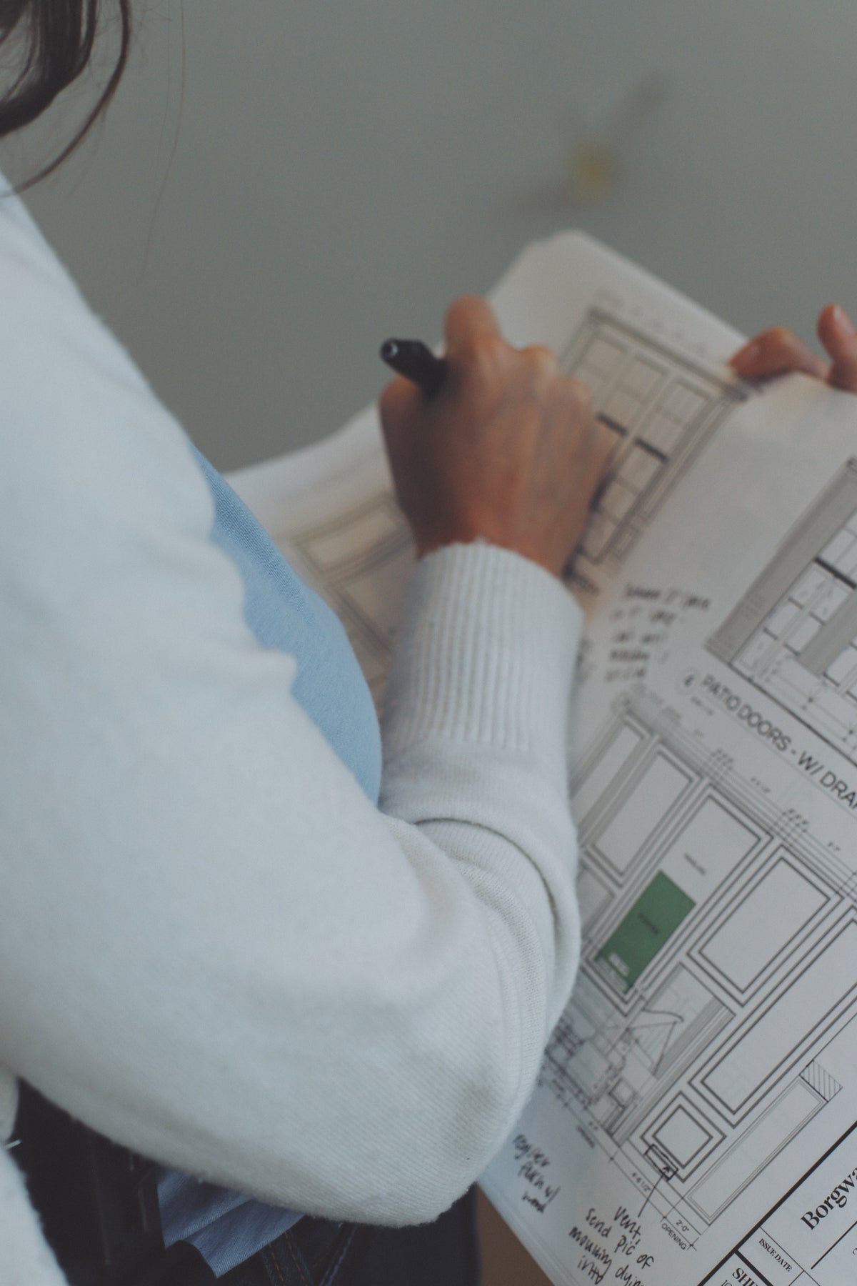 A designer marking up a set of elevation drawings by hand, with notes written in the margins