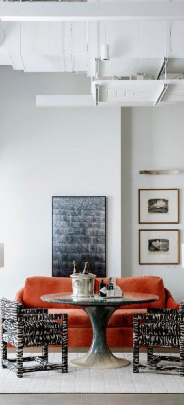 A coral banquette and zebra-print chairs around a round pedestal table