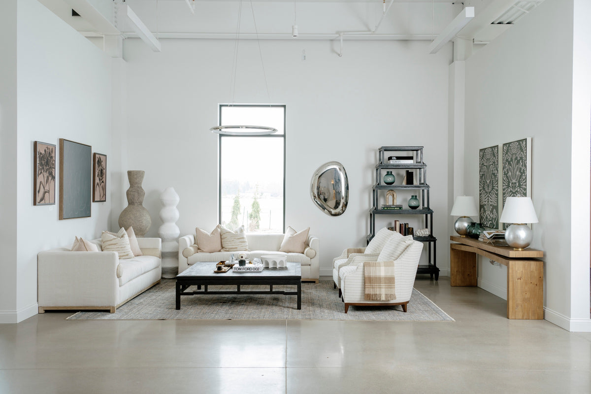A showroom living room in Waukee with a black etagere behind striped chairs on polished concrete floors.