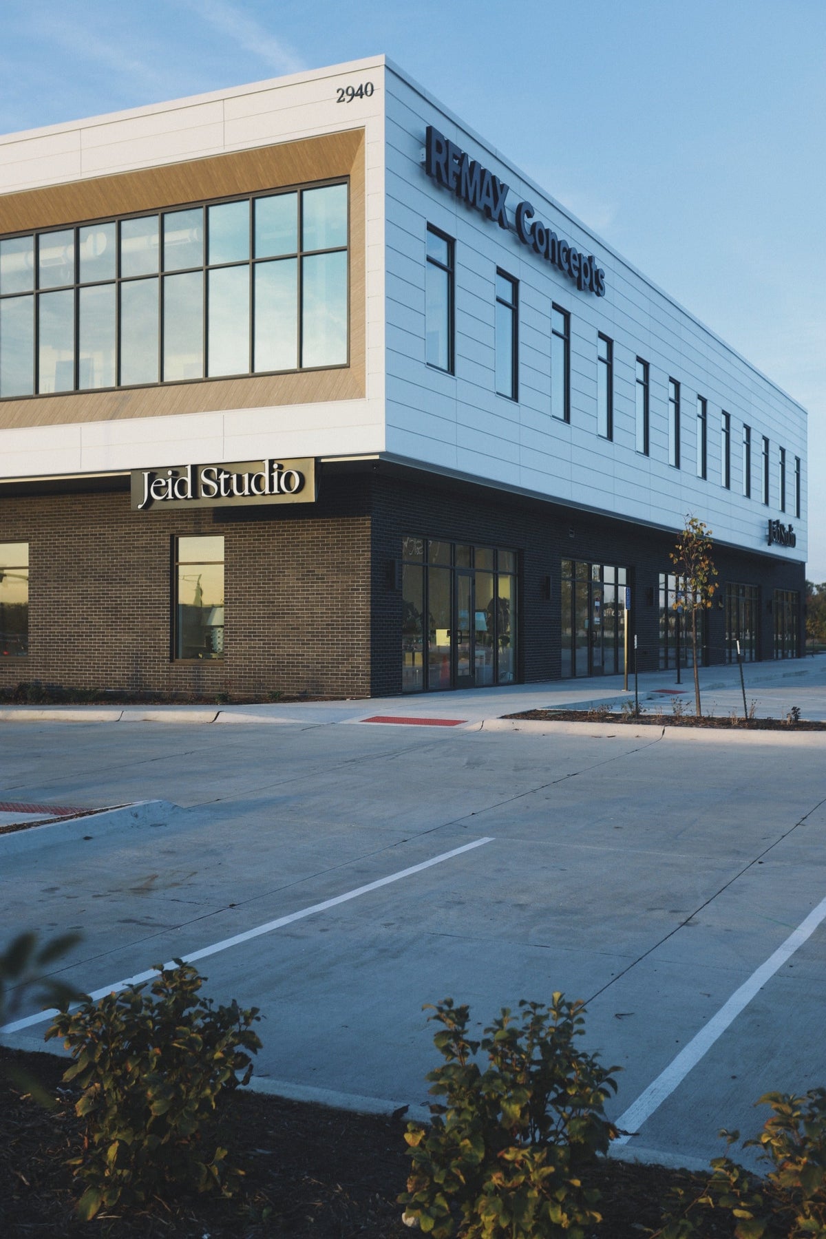 The Jeid Studio exterior in Waukee, with a dark brick storefront under white lap siding and wood-toned trim.