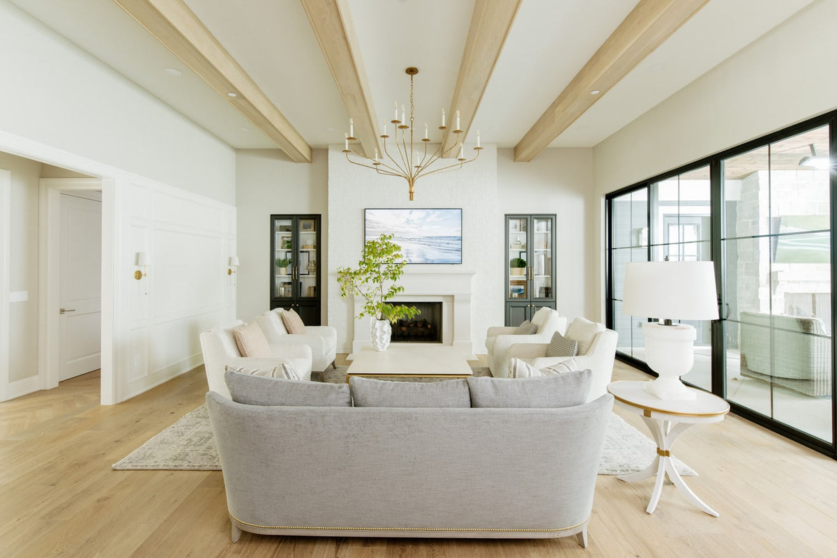 A white living room in Urbandale with light oak ceiling beams above a painted brick fireplace.