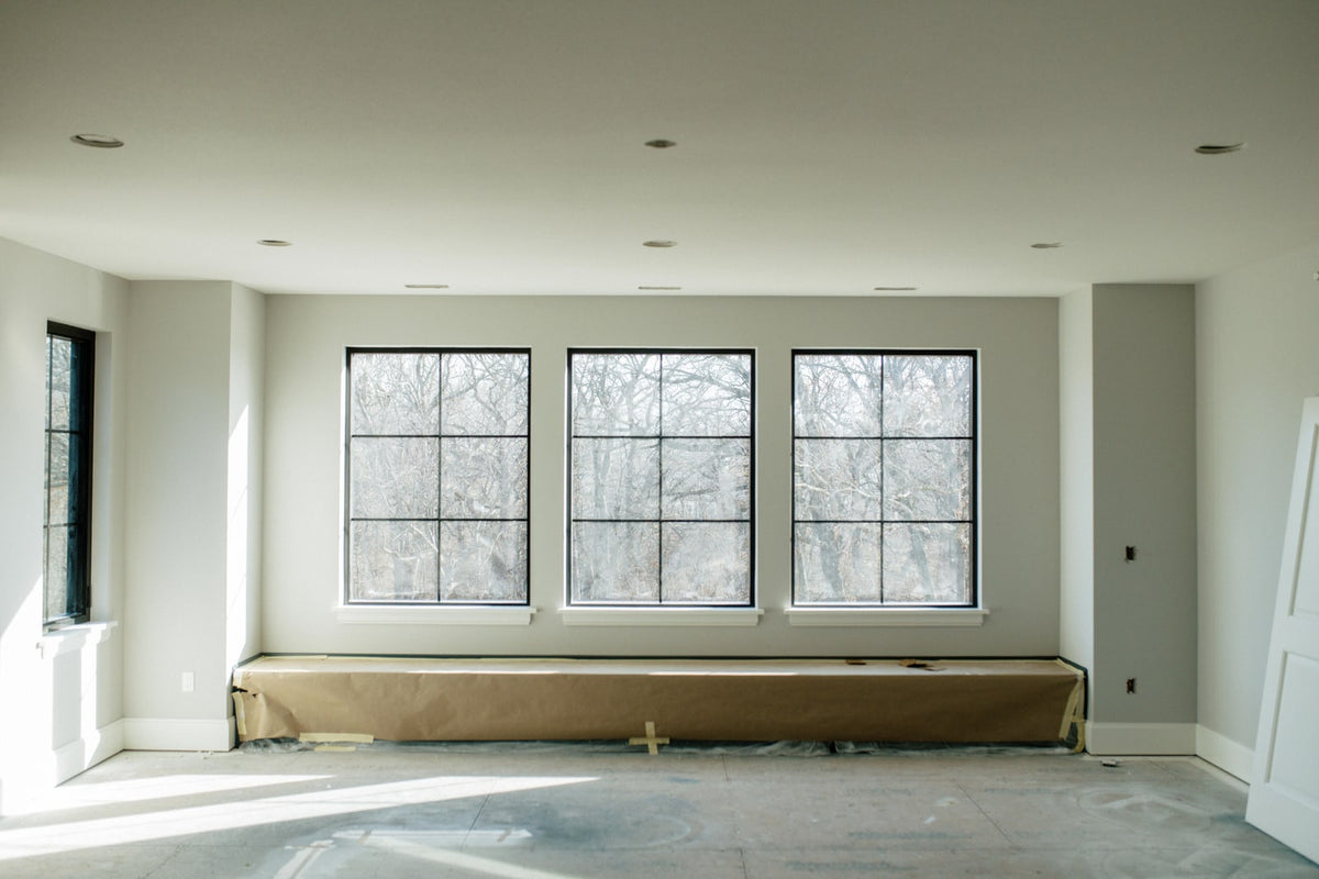 A window wall going in on a house under construction in Urbandale, with three black grid windows and white sills.