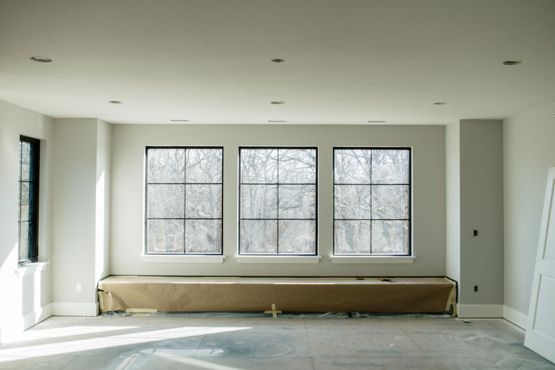 A window wall going in on a house under construction in Urbandale, with three black grid windows and white sills.