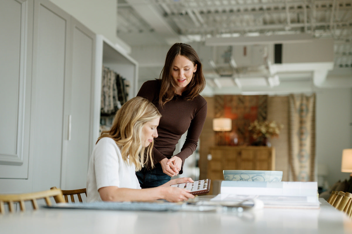 Two designers in the Waukee showroom looking at a hardware sample board at the selections table.