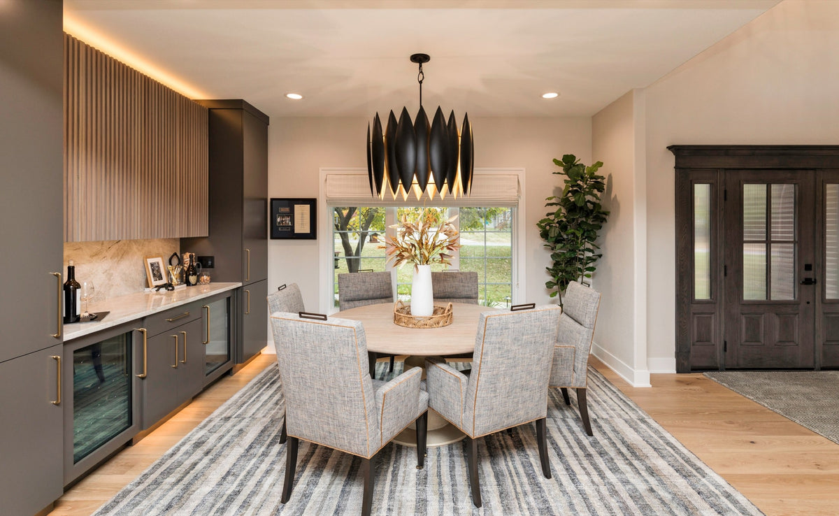 A dining room in Ankeny with a black petal chandelier over a round stone pedestal table.