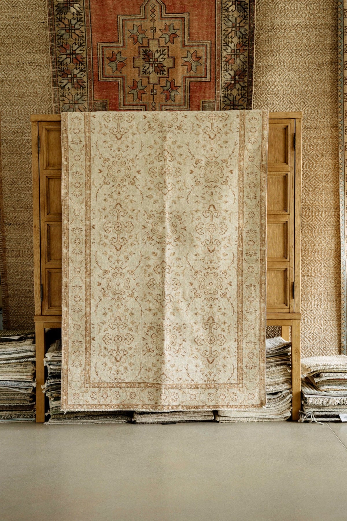 A rug showroom in Waukee with a faded cream and rust wool rug draped over an oak cabinet.